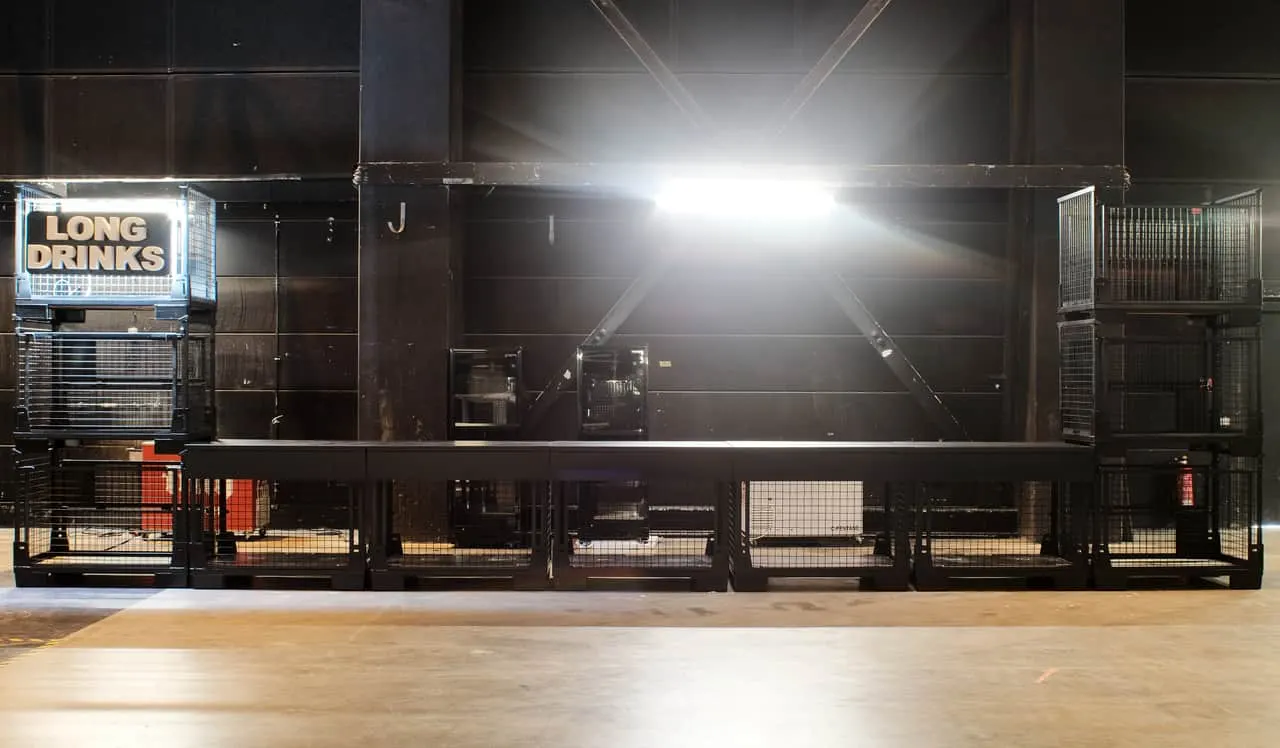 Theke mit Aufsatz — gestapelte Gitterboxen mit Long-Drinks-Schild